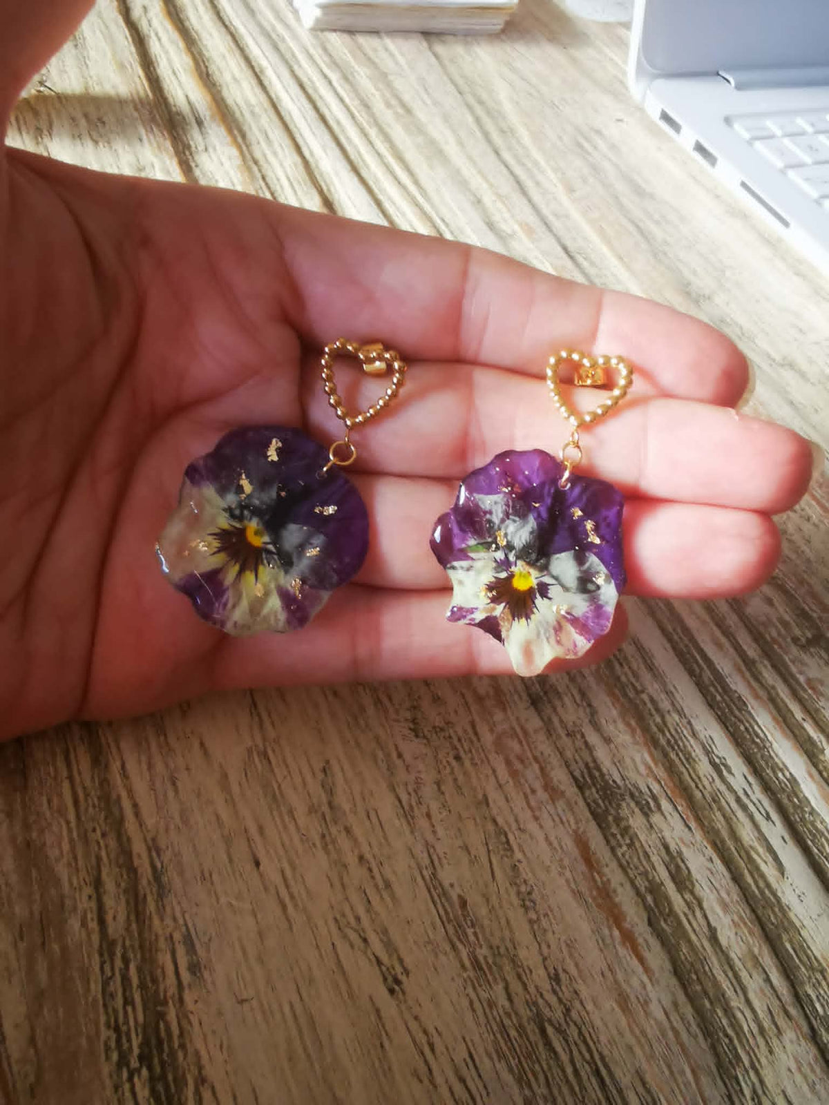 Boucles d'oreilles pensées en fleur véritable portées à la main