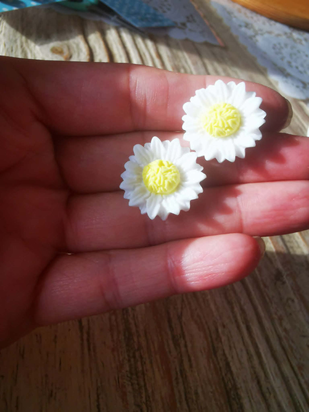 Boucles d’oreilles marguerites blanches et jaunes portées à la main